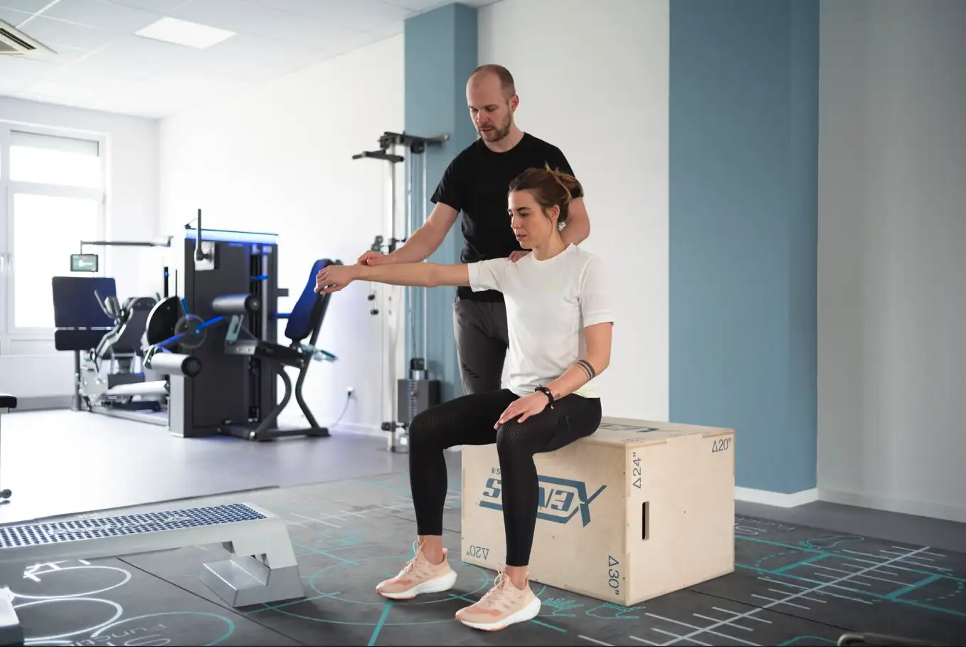 Gregor Mini kontrolliert und korrigiert die korrekte Ausführung einer Übung einer Patientin